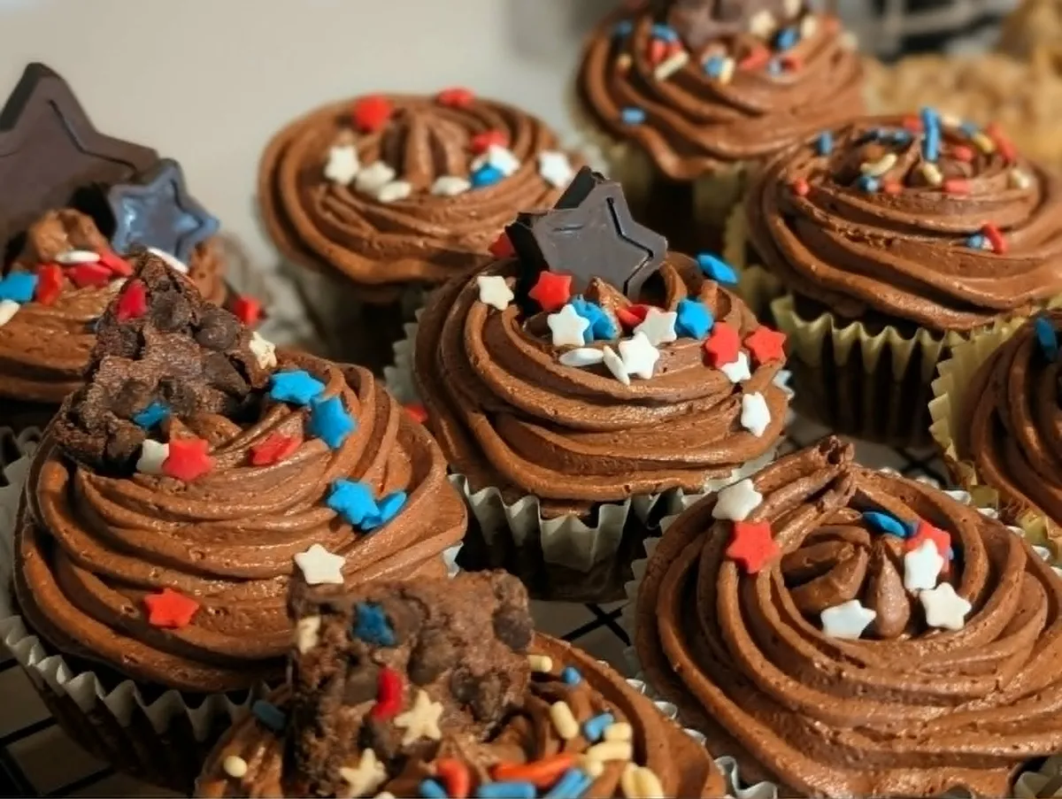 Chocolate cupcakes with swirled chocolate frosting, red, white, and blue star sprinkles, and chocolate star toppers