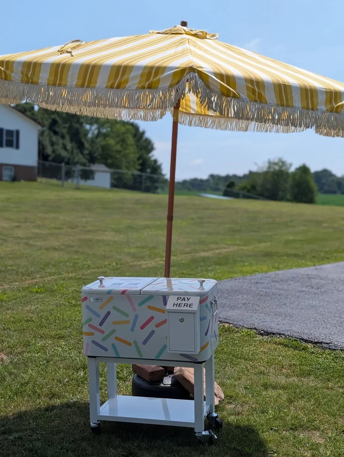 The Hot Off Hotchkiss stand — a sprinkle-painted cooler under a yellow striped umbrella